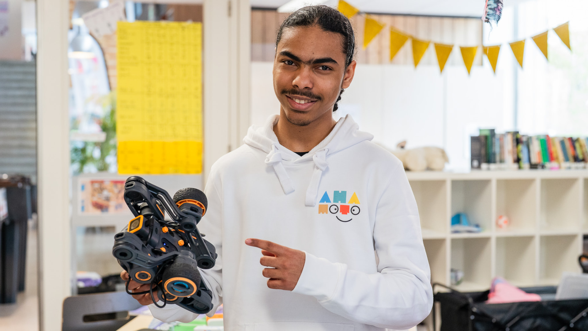 Begeleider van Ahamoto Club helpt een kind met programmeren op een tablet